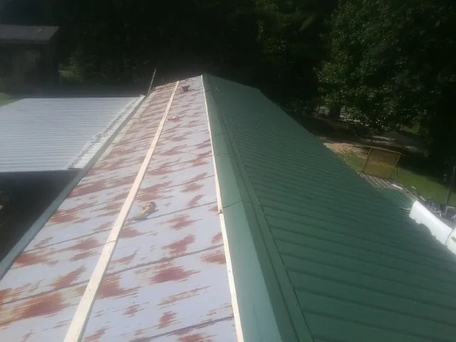 Old rusted panels beside newly installed green metal roofing — Wind Damage Roof Repair by Roofing Brothers in Lawrenceburg