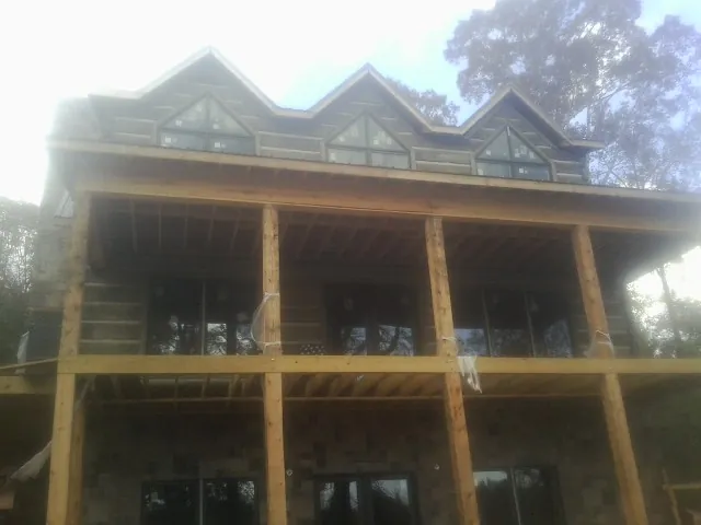 Dormers and porch framing on a large log home under construction — Roof Coating work by our crew in Lawrenceburg