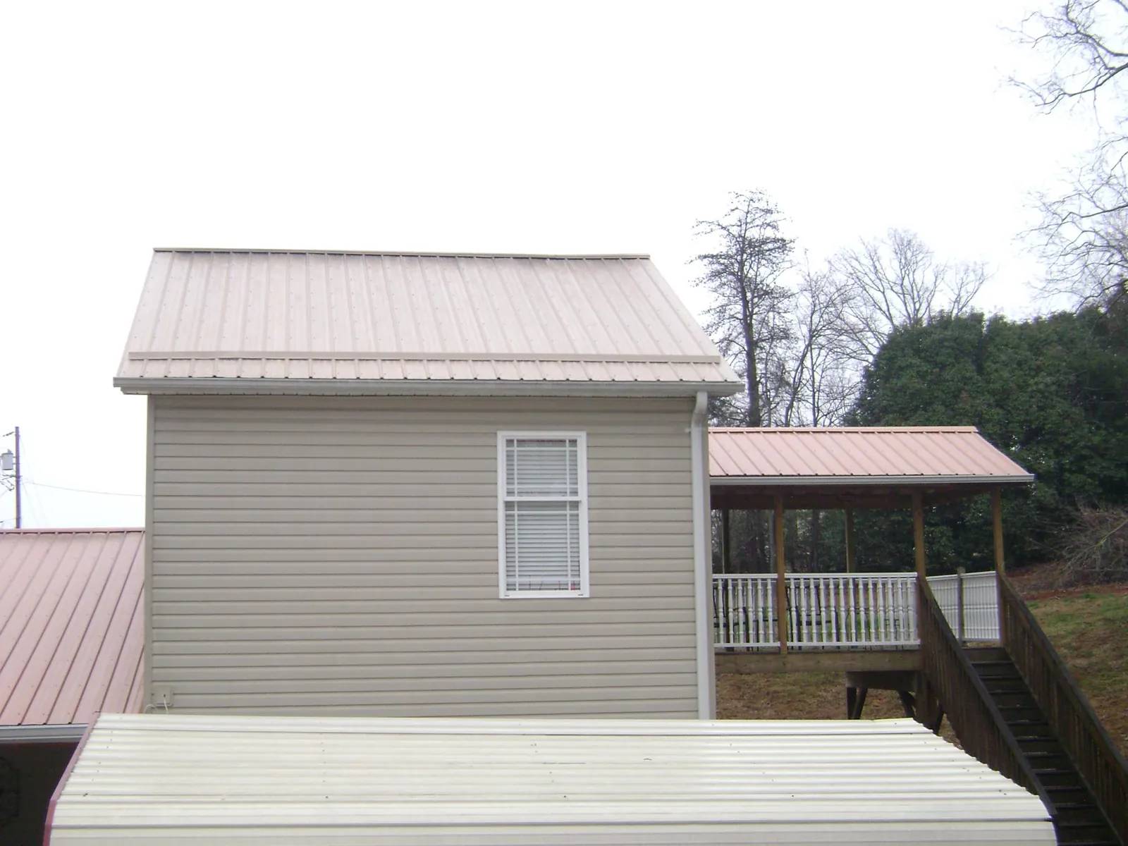 Tan metal roofs on a two story addition and attached porch in Lawrenceburg