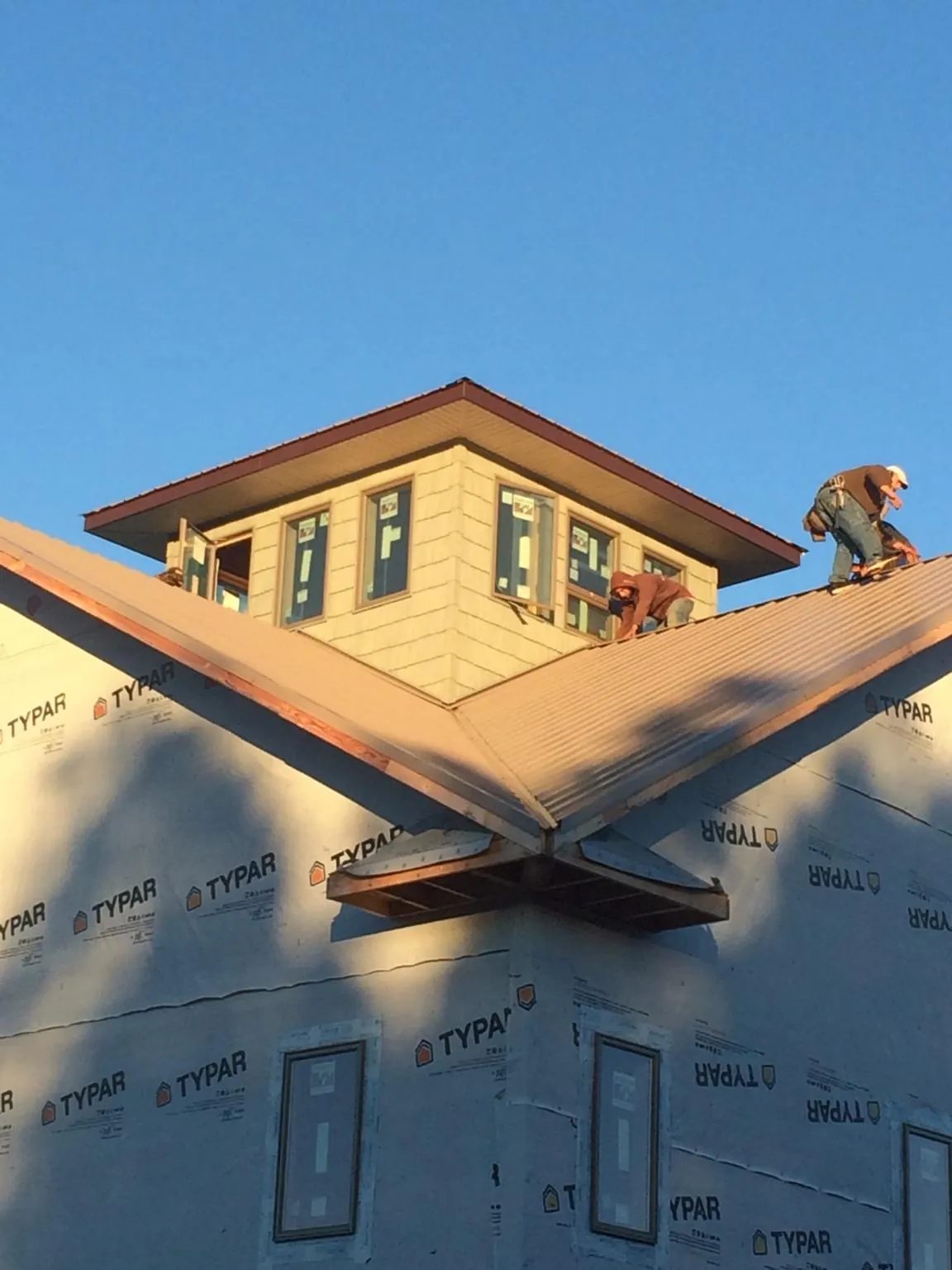 Roofers working around a rooftop cupola on a new metal roof at sunset — Roof Waterproofing in Lawrenceburg by Roofing Brothers